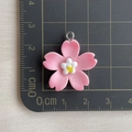 Primer plano de un colgante de flor de cerezo de resina rosa con medidas en una regla - Colgante de flor de cerezo rosa