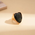 Makro-Detail eines übergroßen herzförmigen grünen Steins in einem breiten Goldring - Gold-Schwarz