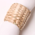 Detailed close-up of handmade woven corn husk napkin ring on a white linen cloth - Corn Husk Thick Woven Style
