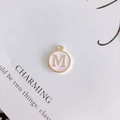 Detail of round pink enamel letter M pendant with gold metal frame for DIY jewelry - Letter M