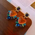 Nahaufnahme der Vintage-Herzohrringe mit bunten Edelsteinen auf einem Holztablett - Oranges Herz-Stil (1#)