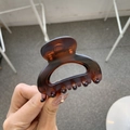 Detailed shot of amber tortoiseshell hair claw clip made of durable resin held in hand - Matte Red Brown