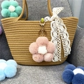Detail showing a cute pink plush flower keychain hanging on a stylish woven straw bag - 1 Piece / Dusky Pink