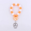 Detail of orange and white silicone bead wristlet with a cartoon dog paw charm and metal ring - Orange