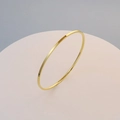 Polished 18K gold plated titanium steel slim bangle on a minimalist round display stand - Inner Diameter 60 / Gold
