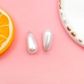 Detail of drop-shaped white pearl charms with silver metal rings for DIY jewelry making - 10x18mm / White K/Silver