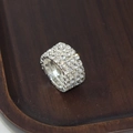 Elegant silver four-row rhinestone stretch ring with sparkling crystals on a wood base - 4 Row Silver Clear Rhinestone Ring