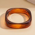 Macro shot of geometric resin bangle with amber marble texture and glossy finish - Amber Pattern