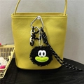 Detail of a yellow leather bucket bag with a black plush cartoon doll charm and mini cart - Black