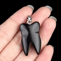 Polished black obsidian tooth-shaped stone pendant with a secure metal clasp hanging - Obsidian