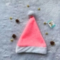 Pink and white plush Christmas hat displayed with pine cones and golden bells - Pink Plush Hat