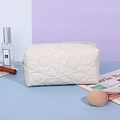 Glossy white heart-embossed makeup bag with Y2K aesthetic on violet background - Pillow Shape / White