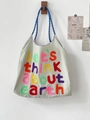 Detail of beige canvas tote with colorful towel embroidery text and blue woven straps - Light Gray