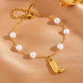 Gold charm bracelet with white pearls and a stylish boot pendant on silk background - Boot Charm Bracelet