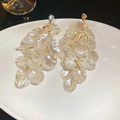 Nahaufnahme der weißen Muschelblüten-Quastenohrringe mit Goldmetall und Kristallen - Silbernadel-Weiß