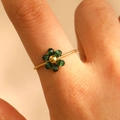 Detailansicht eines grünen Kristallblumenrings mit goldener Textur am Finger - Dunkelgrün