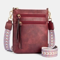 Detail van de wijnrode crossbodytas met dubbele ritsen en een gestructureerde leerlook - Bordeauxrood