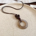 Vista macro del collar con colgante de anillo de resina vintage en plato de cerámica - Estilo de Anillo Redondo Marrón