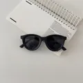 Flat lay of black round silicone sunglasses on a white notebook for kids' fashion - Black