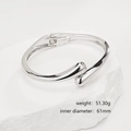Detail of irregular silver crossover open bangle with polished metallic finish on white stone - Minimalist Streamlined Silver Bangle (SL238) / Silver
