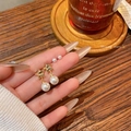 Star and pearl drop earrings set in gold finish shown on a warm lifestyle background - A2202 Gold