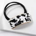 Close-up of marble pattern square buckle on black elastic hair tie with gold metal trim - Black & White