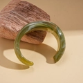 Detail of green acrylic open bangle with marble texture displayed on natural rock - Green