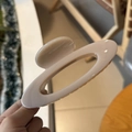 Detailed view of a large cream-colored hollow oval hair claw clip held in hand - Light Nude Pink