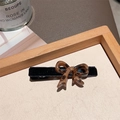 Chic brown leopard print bow hair clip with black velvet base on a wooden tray - Leopard Flocking Bow Clip