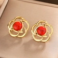 Macro shot of gold floral earrings with red turquoise stone on a textured metallic tray - Gold / Red Turquoise