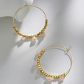Dettaglio di orecchini a cerchio boho dorati con perline quadrate e pietre naturali rosa - Quarzo rosa