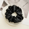 Elegant black satin silk scrunchie placed on a textured white tray accessory holder - Black