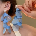 Orecchini a nappa con fiori in tessuto blu e perle indossati da una modella per il resort - Orecchini a nappa con petali in tessuto e perle (29#) / Blu