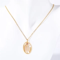 Detail of gold oval zodiac pendant with M letter and pink stone on a white bust - Scorpio