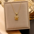Gros plan du pendentif patte de chat doré avec zircon cœur jaune sur boîte velours - Chaîne à billes / Or + Jaune
