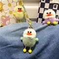 Detail showing three colorful plush duck keychains with soft faux fur and metal rings - Green