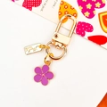 Golden keychain featuring a purple enamel flower charm and handmade tag on white background - Purple