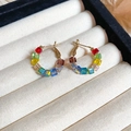 Macro detail of colorful square glass beaded hoop earrings on a velvet jewelry pad - Colorful