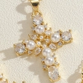 Macro detail of 14K gold plated cross pendant with pearls and sparkling zircon stones - White