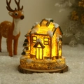 Detail of glowing Christmas resin house with warm LED light and faux snow on wood base - 9.5x7.5x10cm / Style A