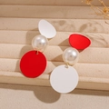 Detalle de pendientes asimétricos con perlas rojas y blancas en una bandeja de terciopelo - Poste de pendiente de plata - Rojo