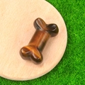 Carved tiger eye stone bone figurine with golden luster on a rustic wooden base - Tiger's Eye