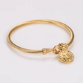 Dettaglio macro del bracciale a spirale dorato con ciondolo religioso a rilievo di santo - Stile Ciondolo Santo Religioso