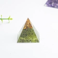 Pyramid resin decor with green natural crystal stones and gold foil flakes on white surface - Peridot