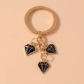 Dettaglio portachiavi dorato con tre ciondoli a forma di diamante in smalto nero su arancio - Nero