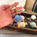 Detail of blue plush ice cream keychain with golden ring and tassel on a cozy background - Blue
