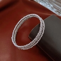 Makroaufnahme eines silbernen mehrlagigen Armbands mit strukturierter Perlenoberfläche - Silber