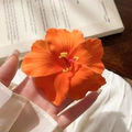 Detail of an orange hibiscus fabric hair clip with realistic textures and yellow stamens - Orange