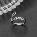 Macro shot of silver stainless steel adjustable ring with Cancer cursive lettering - Adjustable Open / Cancer Steel