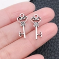 Pair of vintage silver alloy key pendants for DIY jewelry making held in hand - Miniature Key 9x21mm (6722)